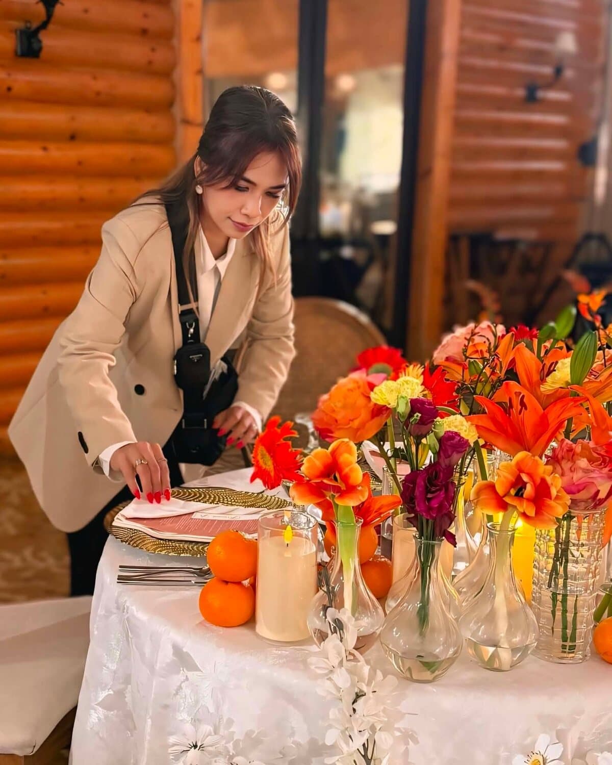 Jomai Arnaiz laying a place setting at a table dressed with orange florals