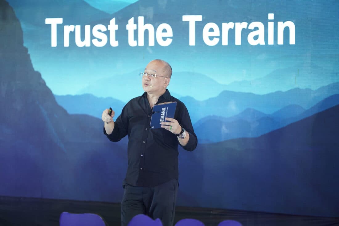 A speaker mid-talk against the mountains