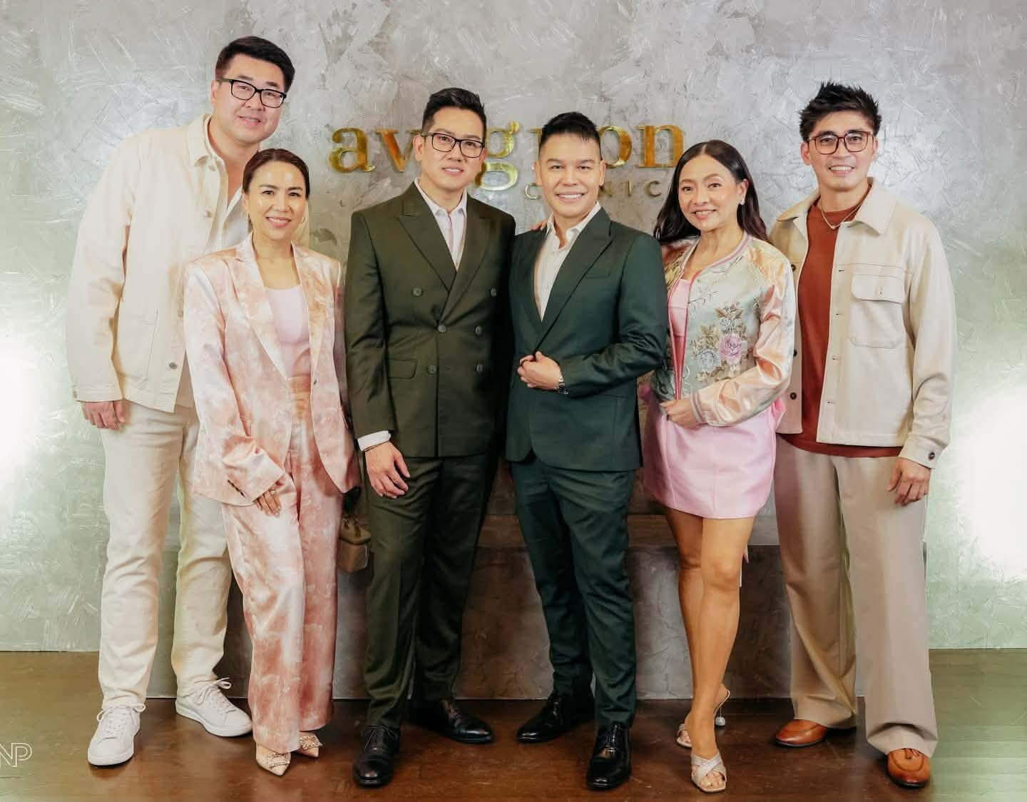 Six guests photographed together against the clinic's signage wall