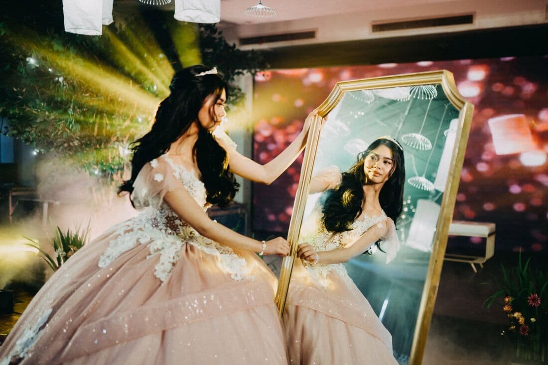 A debutante beside her portrait under stage lights
