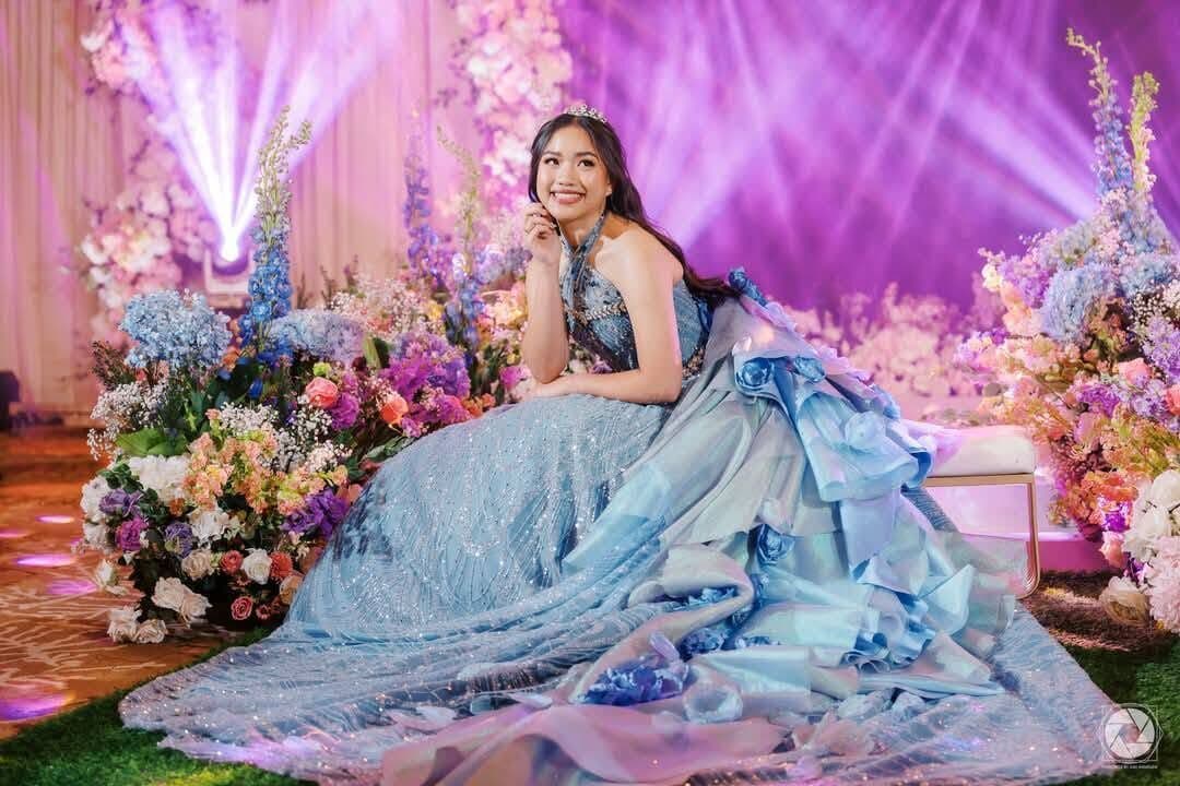 A debutante in a blue gown on a floral set