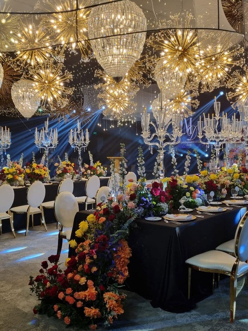 A long reception table beneath chandeliers