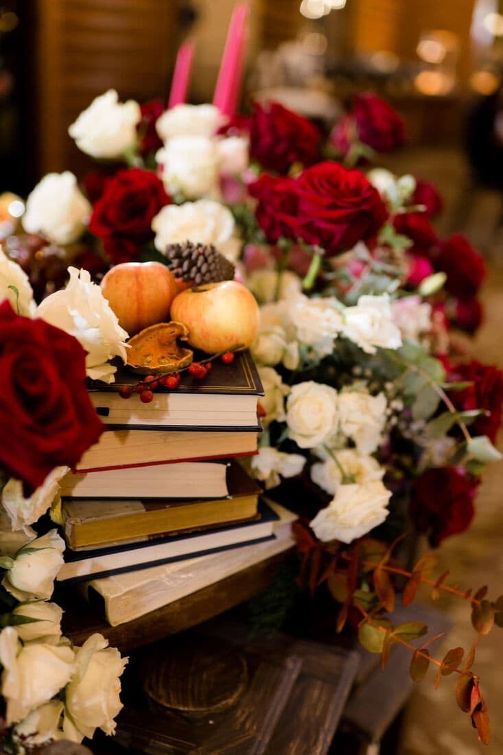 Roses and pumpkins stacked on a pile of books
