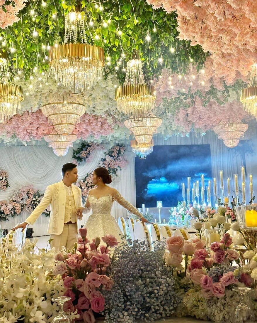 A couple descending through a hall of blush florals