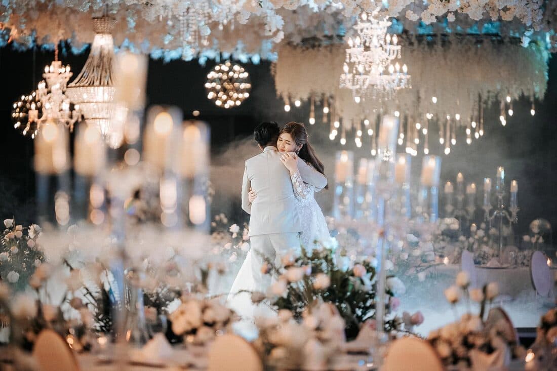 The couple dancing beneath chandeliers and candlelight