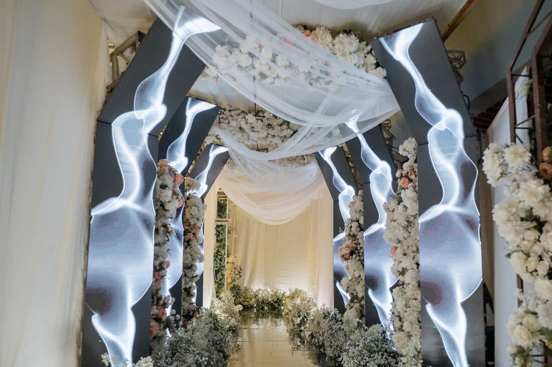An arch of lit fabric and white blooms