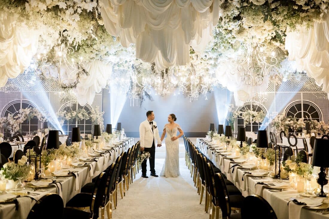 The couple walking between long banquet tables