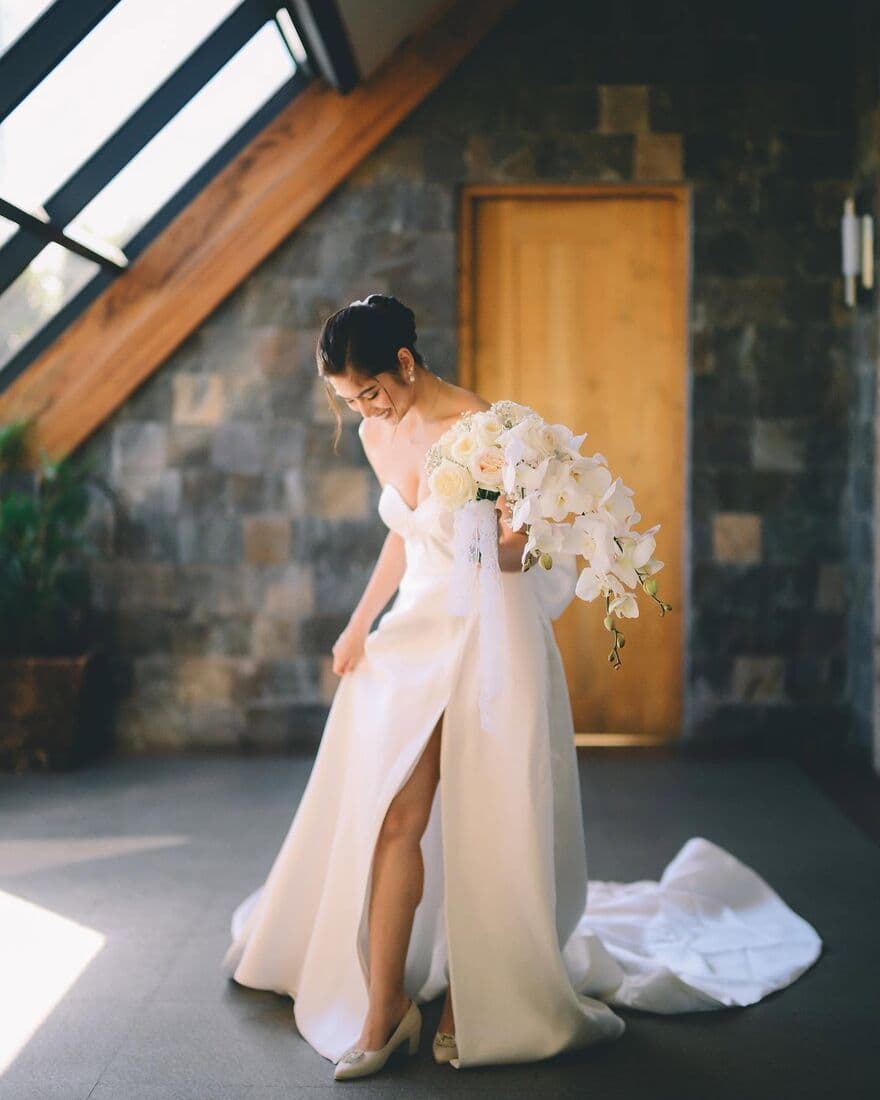 A bride in her gown beside a stone doorway