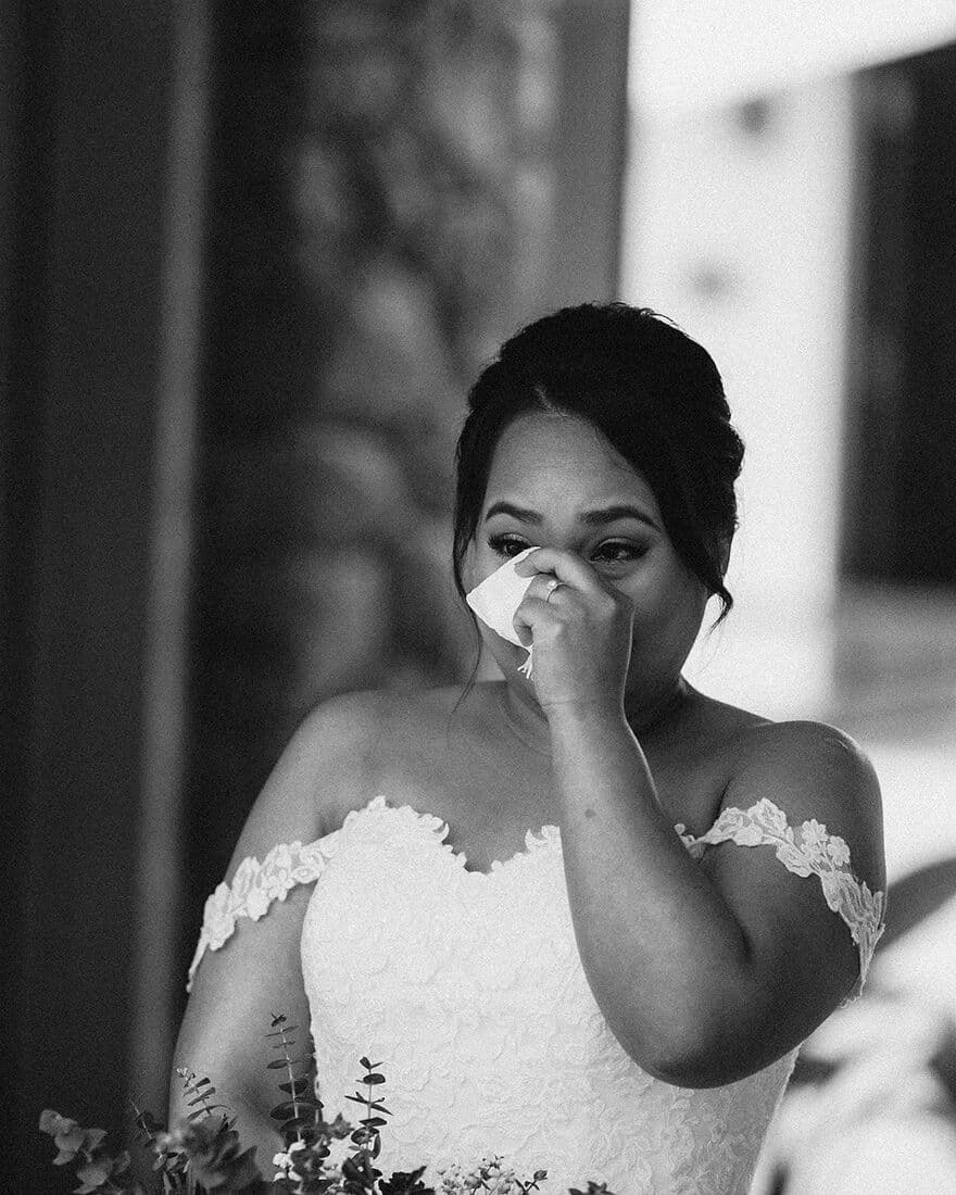 Black and white photograph of a bride wiping away a tear
