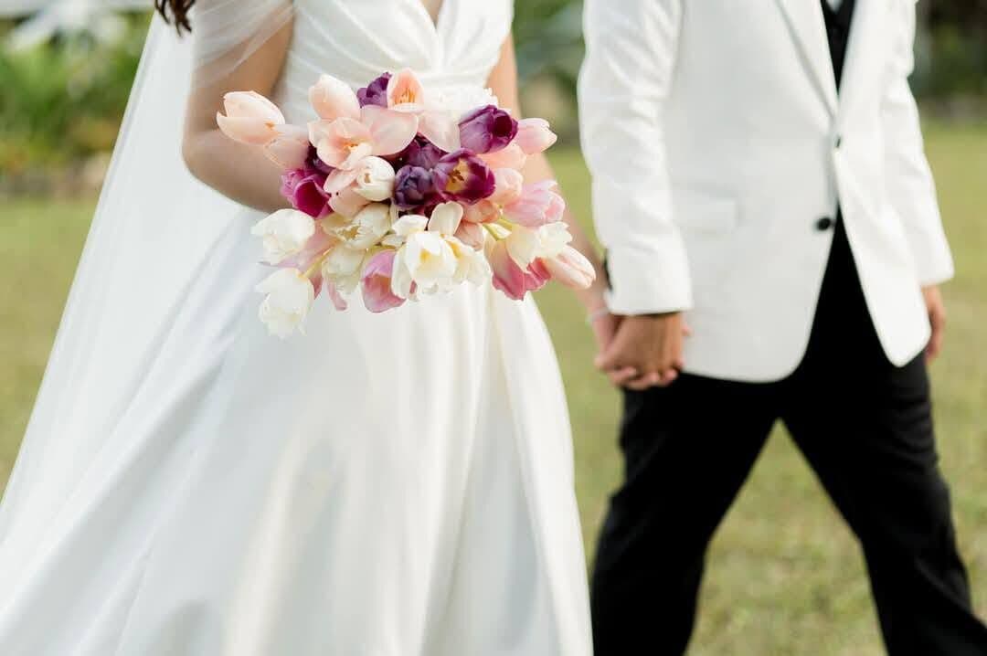 A couple walking, the bride holding her bouquet behind her