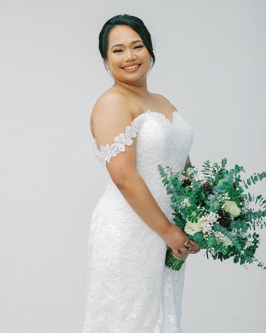 A bride holding a green and white bouquet