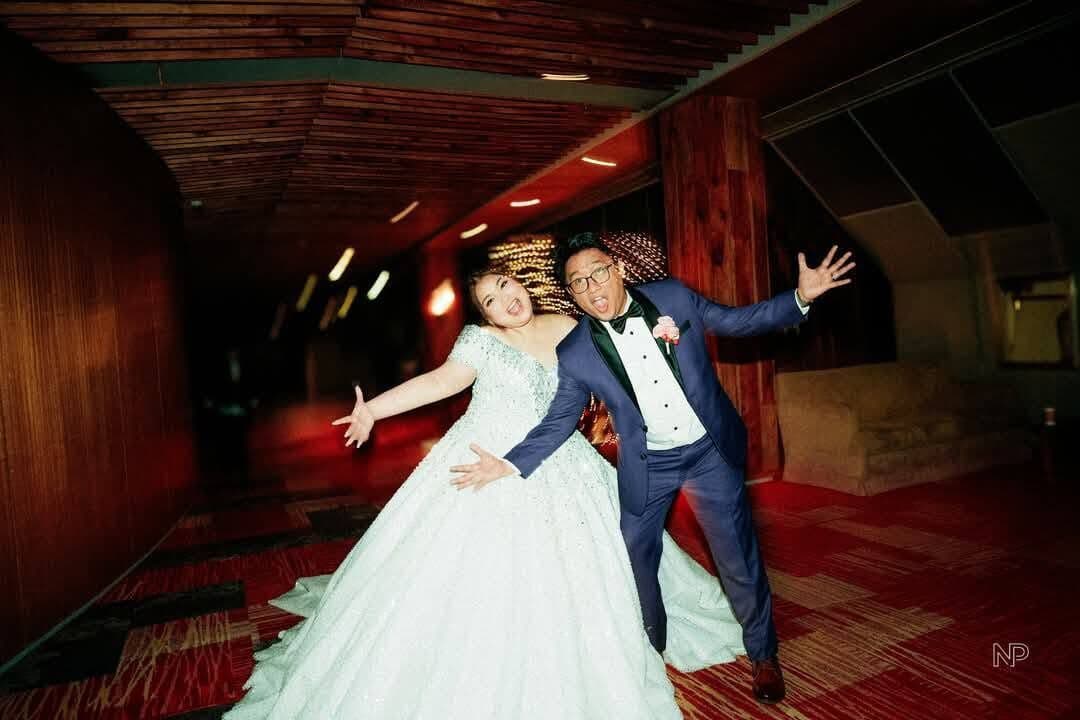 A couple in a dark hallway, arms wide