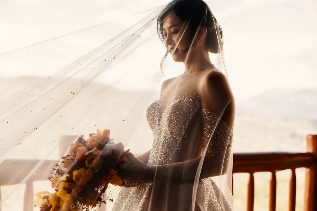 A bride beneath her veil holding a bouquet