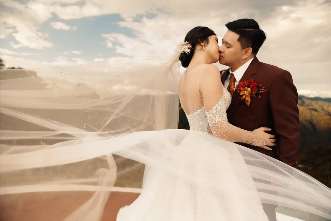 The couple kissing under a billowing veil